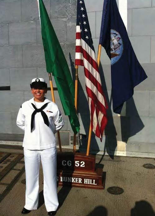 Indira Tapias in navy uniform standing in front of flags