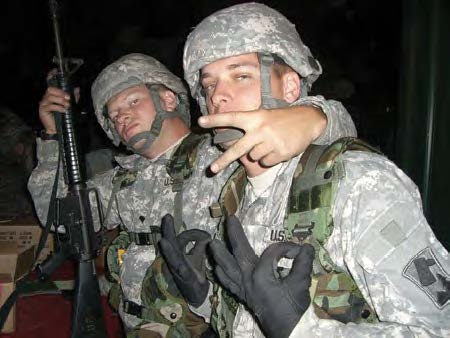 Jesse Babcock in fatigues posing with a fellow soldier holding a gun