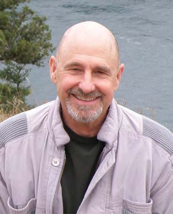 Jim Wheeler in a gray coat in front of a body of water