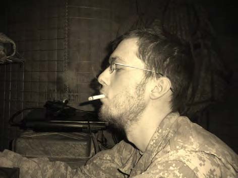 Sepia toned Keith Fletcher in profile wearing fatigues and smoking a cigarette