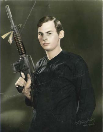 A young Michael Novotny holding an assault rifle