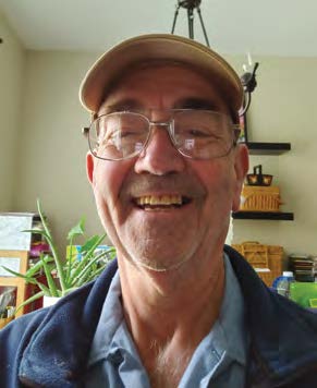 Russ Kapp wearing a cap smiling in front of house plants